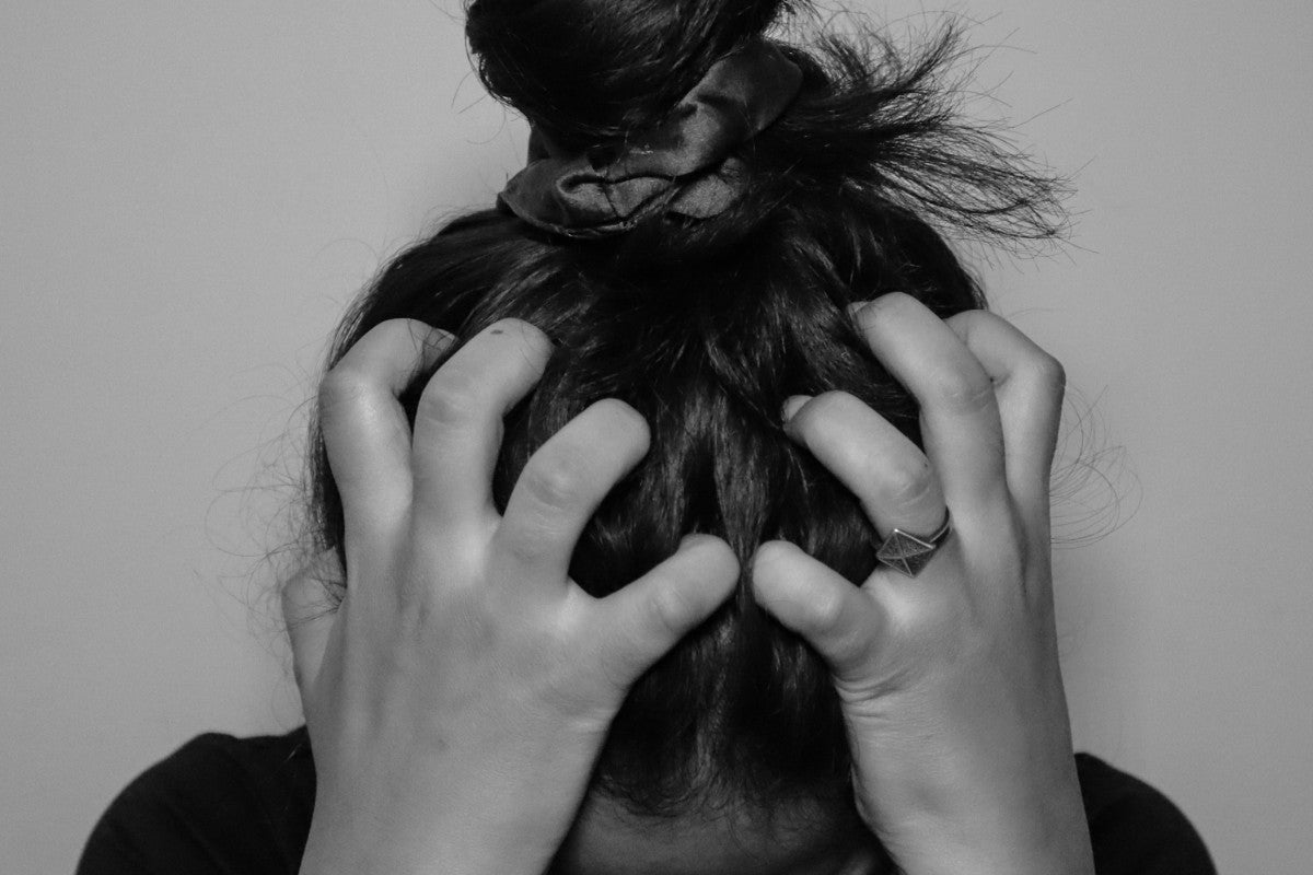 Black and white photo of a woman gripping her hair with both hands, representing the physical and emotional toll of elevated cortisol and chronic stress