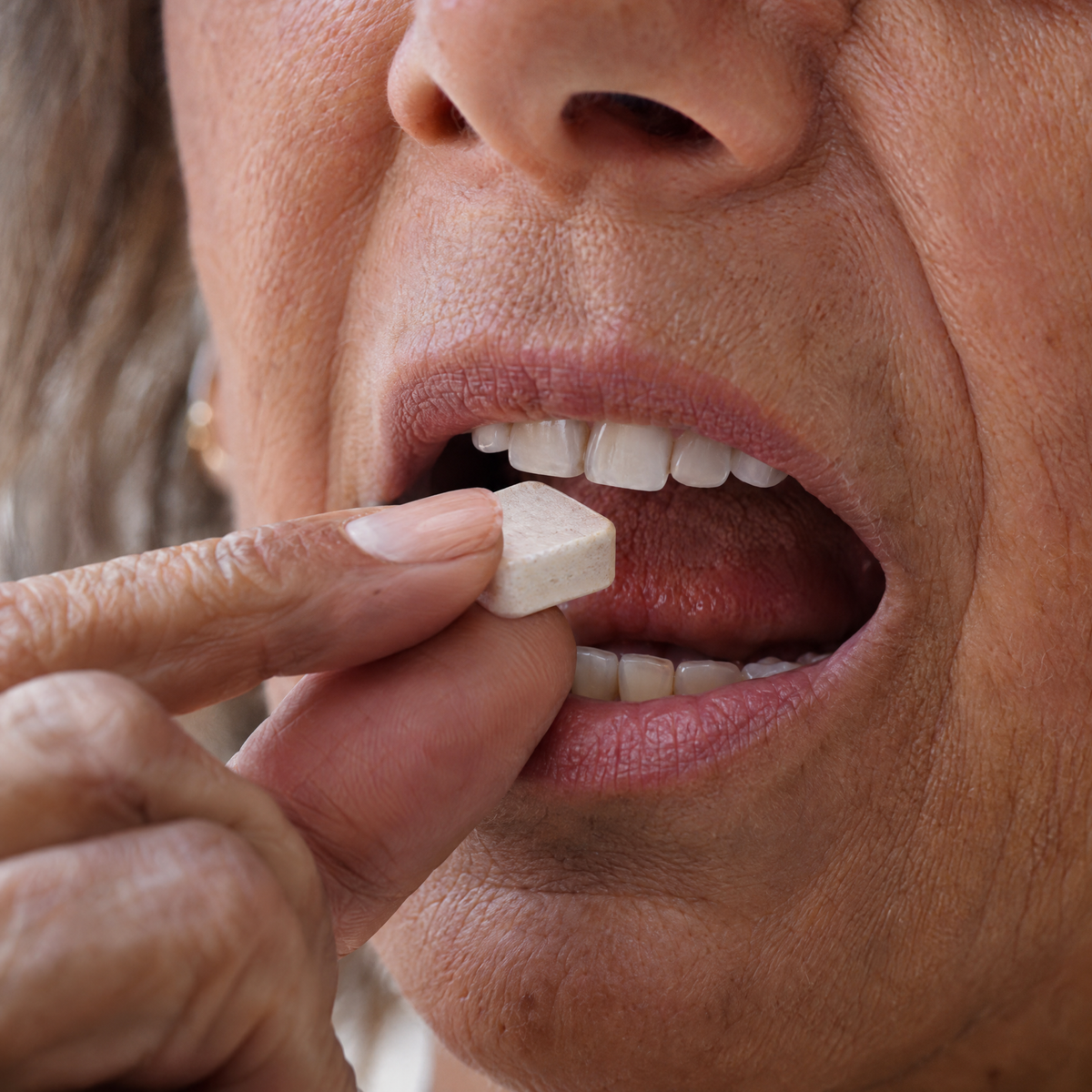 Woman placing a troche in her mouth