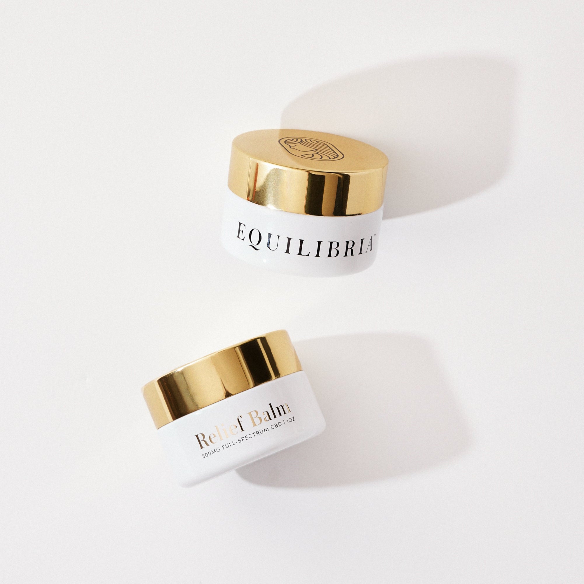 Two jars of Equilibria CBD Balm with gold lids on a white background