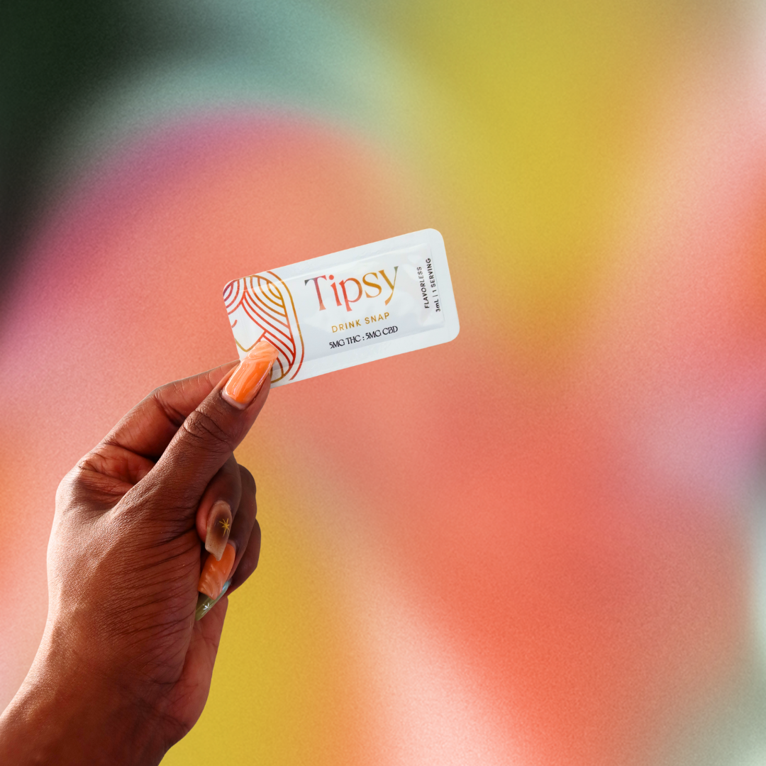 Hand holding a 'Tipsy' Drink Snap against a colorful blurred background