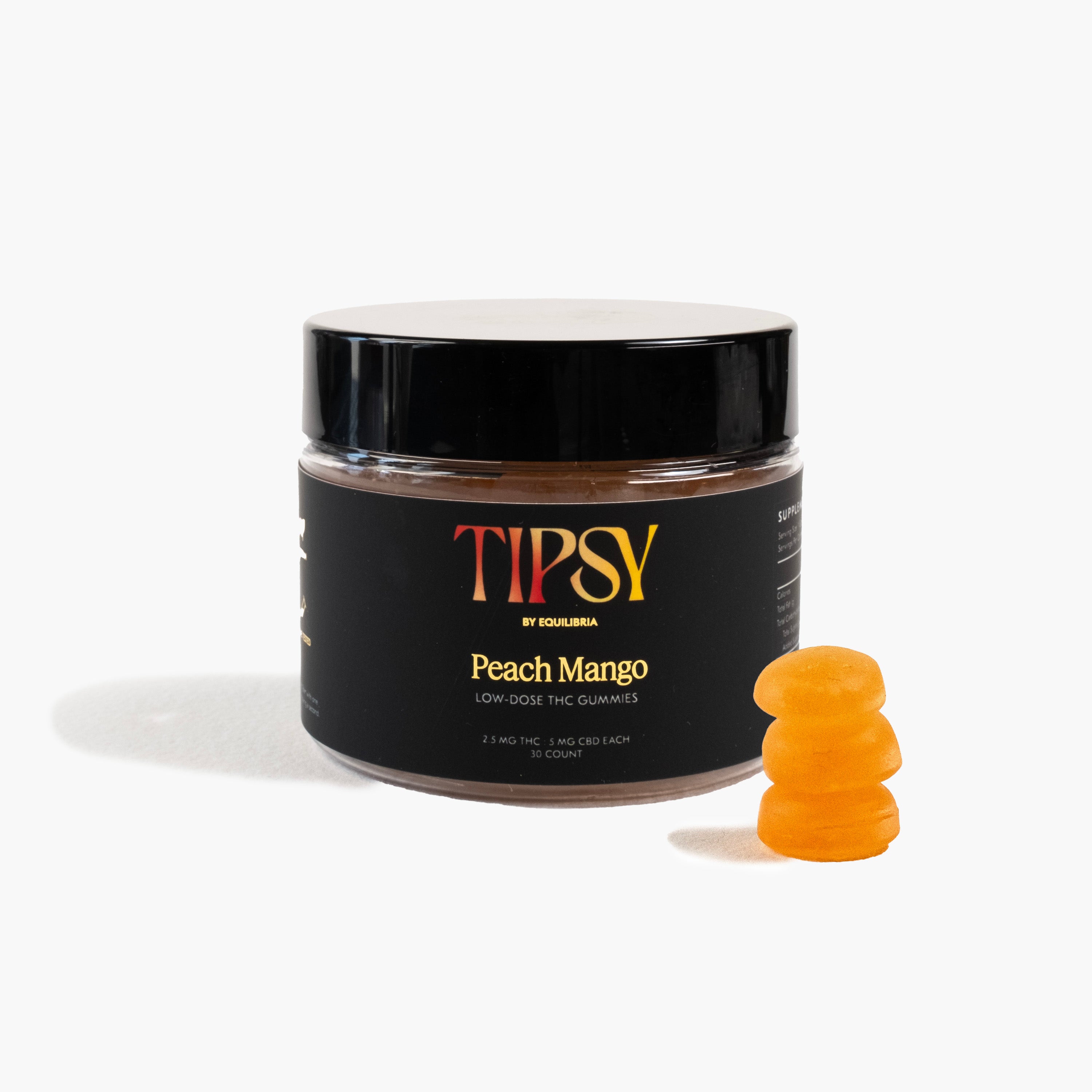 A jar of Tipsy Peach Mango THC Gummies with a stack of orange gummy candies in front of it.