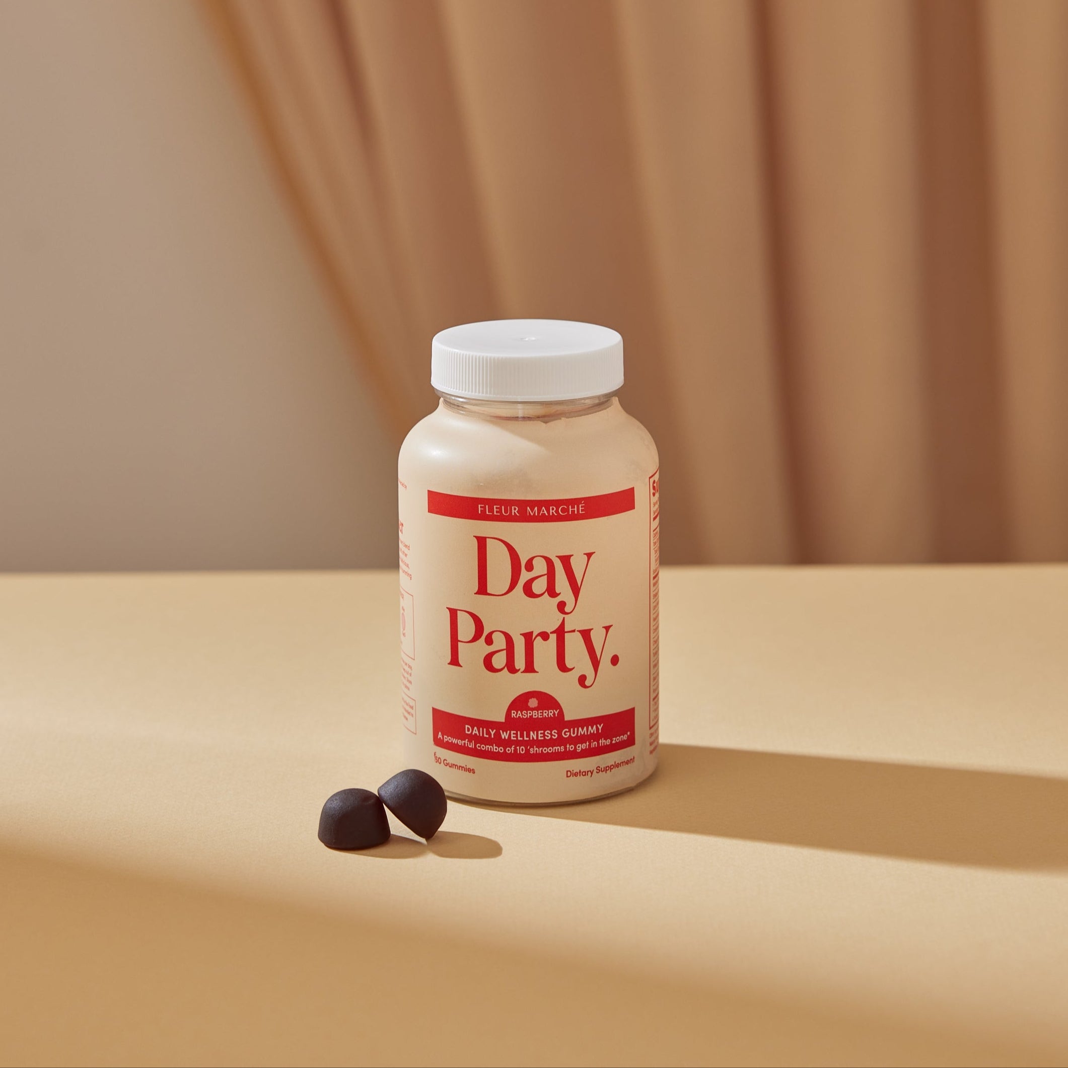 Bottle of 'Day Party' supplement on a beige surface with a brown curtain background
